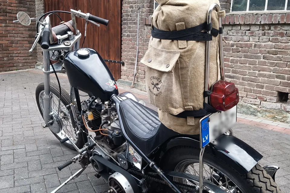 Motorrad von hinten vor einer Backsteinwand, auf dem Heck die Sissybar Bag aus Canvas mit Siebdruck-Logo.
