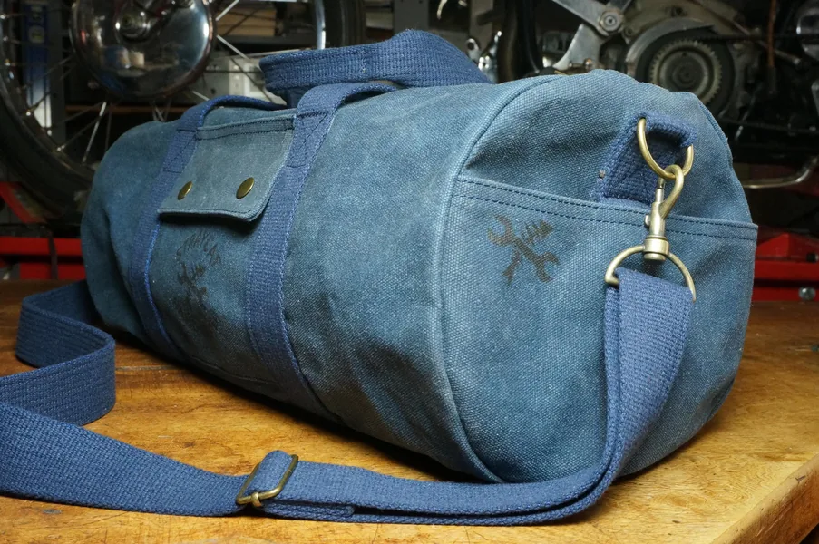 Blaue Duffle Bag aus gewachstem Canvas auf einer Werkbank.